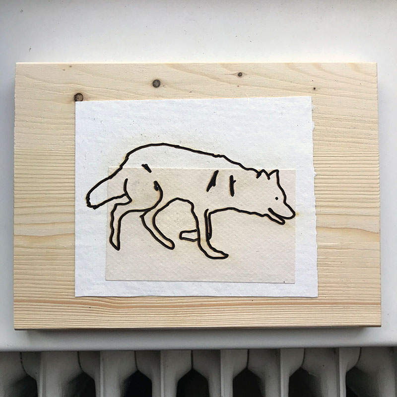 A single wolf design lasercut into paper on wood