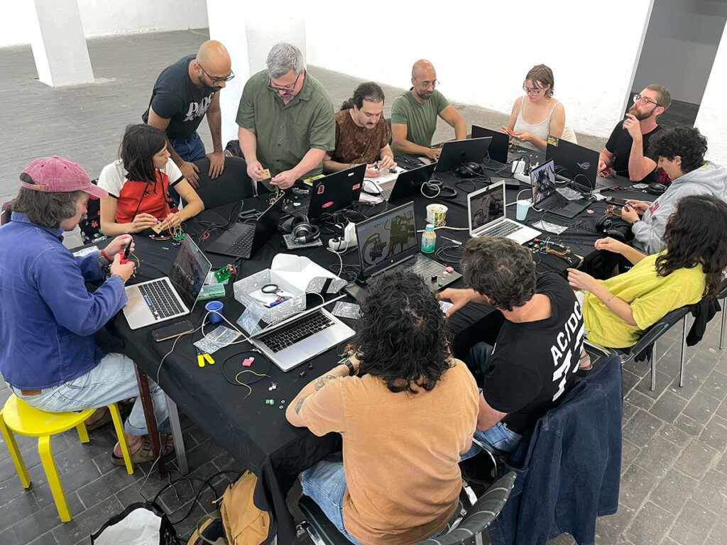 An overhead view of a table with laptops and students working on electronics