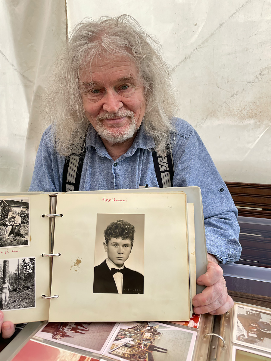 Man with white hair holding a photo of himself younger